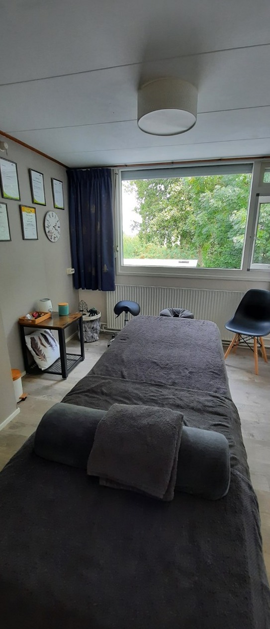 Behandelruimte met massagetafel, handdoeken en een raam