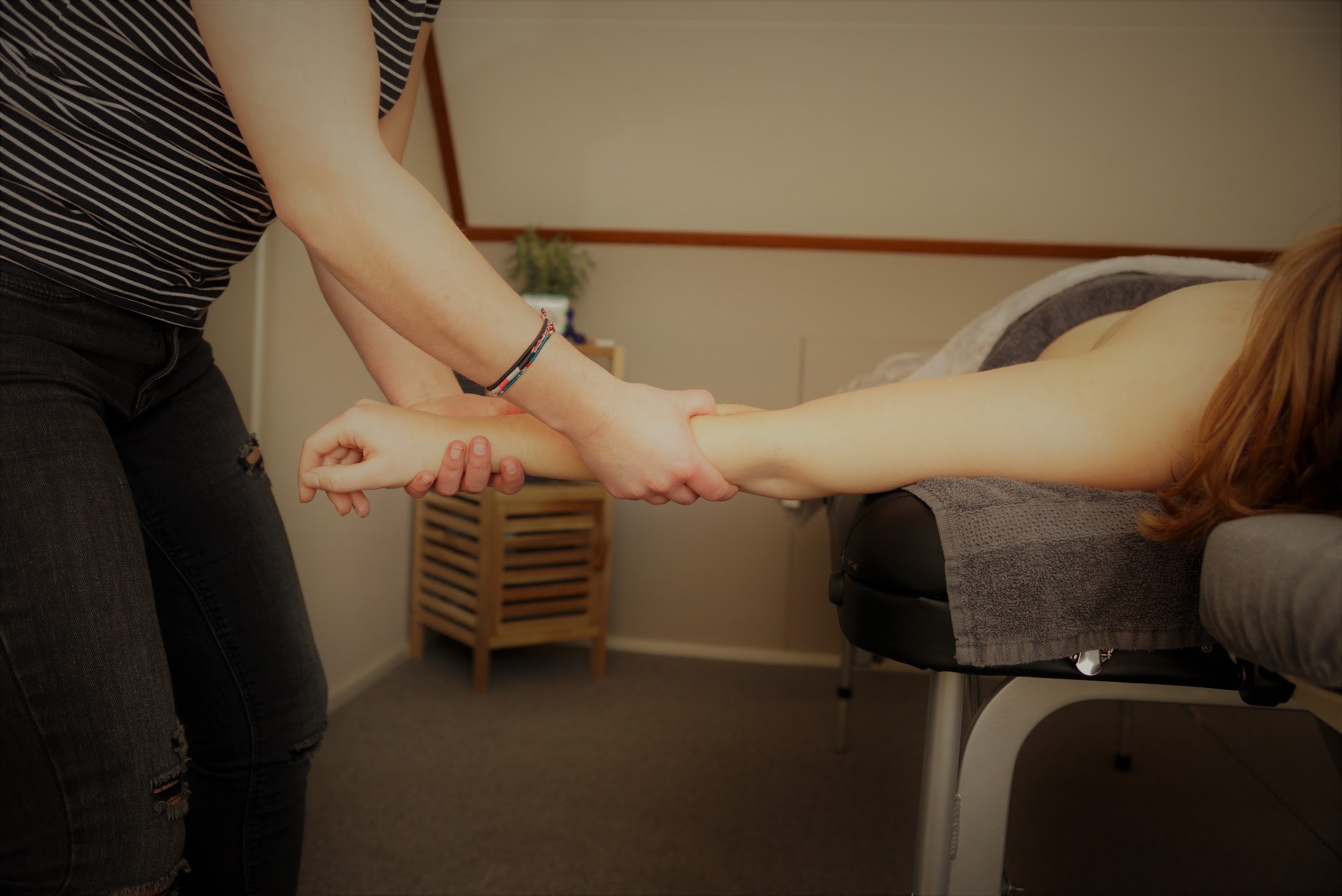 Denise rekt de arm van een cliënt die op de massagetafel ligt